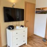 Schlafzimmer mit TV, Schrank und Tür. Wandbild zeigt Leuchtturm.