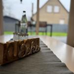 Holztablett mit Schriftzug auf Tisch, Blick auf Gartenhaus im Hintergrund.