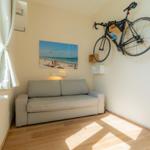 Ein Raum mit Sofa, Wandbild und aufgehängtem Fahrrad.
