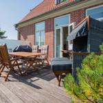 Terrasse mit Holztisch, Stühlen und Liege. Hintergrund: roter Ziegelbau mit Fenstern.