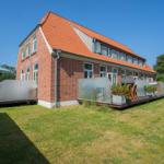 Rotes Ziegelhaus mit Terrasse und Garten. Moderne Pavillons und Sitzgelegenheiten.