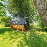 Holz-Kuppelhaus mit Dach auf grünem Rasen zwischen Bäumen