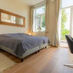 Schlafzimmer mit Bett, Spiegel, Schreibtisch und Balkontür.