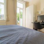 Schlafzimmer mit Bett, Schreibtisch und Fenster zum Garten.