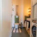Badezimmer mit Toilette, Dusche, Waschmaschine und Handtuchkorb.