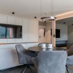 Modern eingerichtetes Wohn- und Esszimmer mit TV, Tisch und Stühlen.