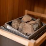 Steine in einem Metallbehälter in einer Holzsauna