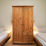 Zwei Einzelbetten flankieren einen Holzschrank mit Schubladen.