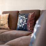 Ein braunes Sofa mit zwei Kissen, eines mit Segelschiff, das andere mit Ruder