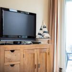 TV auf Holzschrank mit Segelschiffmodell und Blick auf Terrasse