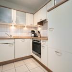 Küche mit weißen Schränken, Holzoberflächen und integriertem Ofen.