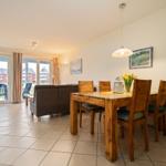 Wohn- und Essbereich mit Holztisch, Sofa und Blick auf Terrasse.