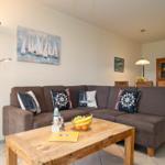 Wohnzimmer mit Sofa, Holztisch und Segelboot-Bild an der Wand.