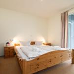 Schlafzimmer mit Holzbett, Schrank und Balkontür.