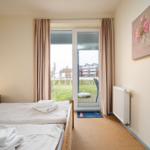 Schlafzimmer mit Doppelbett, Blick auf Terrasse und Garten.