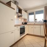 Küche mit Holzschrank, Herd und Fenster