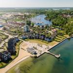 Aerial view of a waterfront residential area with houses, docks, and a marina.