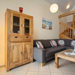 Wohnzimmer mit Sofa, Holzregal und Treppe zur oberen Etage.
