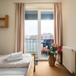Schlafzimmer mit Balkon, Bett, Blumen und Heizkörper.