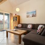 Wohnzimmer mit Sofa, Couchtisch und Balkontür. Wandbild und Holzregal sichtbar.
