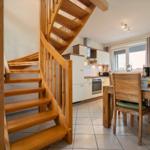 Holztreppe führt zur Küche und Esszimmer mit Tisch und Stühlen.