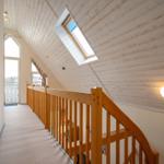 Haus mit Holzverkleidung, Dachfenster und Holzgeländer im Flur
