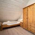Schlafzimmer mit Holzbett, Kleiderschrank und Holzwand
