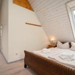 Schlafzimmer mit Dachschrägen, Bett und Fenster.