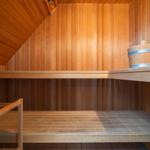 Sauna mit Holzwand, Sitzbänken und Eimer