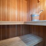 Sauna mit Holzwand, Sitzbank und Eimer mit Löffel
