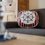 Ein Kissen mit Ruderhausmotiv auf einem Sofa.