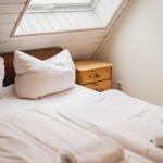 Schlafzimmer mit Dachschrägen, Bett, Nachttisch und Dachfenster.