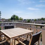 Terrasse mit Tisch und Stühlen, Blick auf Wohnhäuser und einen Turm.