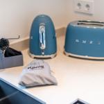 Küchenzeile mit Kaffeemaschine und Toaster. Reinigungsmittel und Tasche für Gäste.