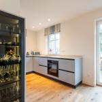 Küche mit Glasvitrine, Holzboden und Fenster zum Garten