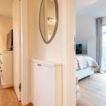 Schlafzimmer mit Bett und Fenster. Flur mit Spiegel und Schrank.