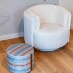 Runde weiße Sitzgelegenheit mit buntem Hocker auf Holzboden.