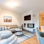 Wohnzimmer mit Sofa, Sesseln, Kamin und Fernseher.