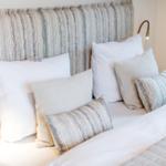 Bettkopfteil mit gemustertem Stoff und Kissen in verschiedenen Farben und Mustern.