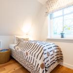 Ein Schlafzimmer mit Bett, Fenster und Holzboden.