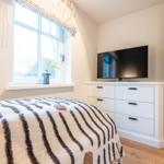 Schlafzimmer mit Bett, Fernseher und Fenster