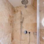 Duschkabine mit Duschbrause, Handdusche und runden Spiegel.