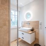 Badezimmer mit Waschbecken, Spiegel und Fenster.