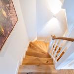 Holzgetriebene Treppe mit weißer Balustrade und Wandbild