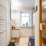 Badezimmer mit Dusche, Waschbecken und Heizkörper.