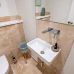 Badezimmer mit Waschbecken, Spiegel und Toilette.