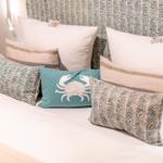 Bettkopfteil mit Muster, mehrere Kissen mit verschiedenen Mustern und einem Krabbenmotiv.