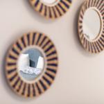 Wand mit drei runden Spiegeln mit geflochtenem Rahmen.