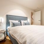 Schlafzimmer mit Bett, Nachttisch und Schrank. Hintergrund zeigt eine Treppe.