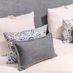 Bettkopfteil mit Kissen in Grau, Weiß und Blau-Muster.